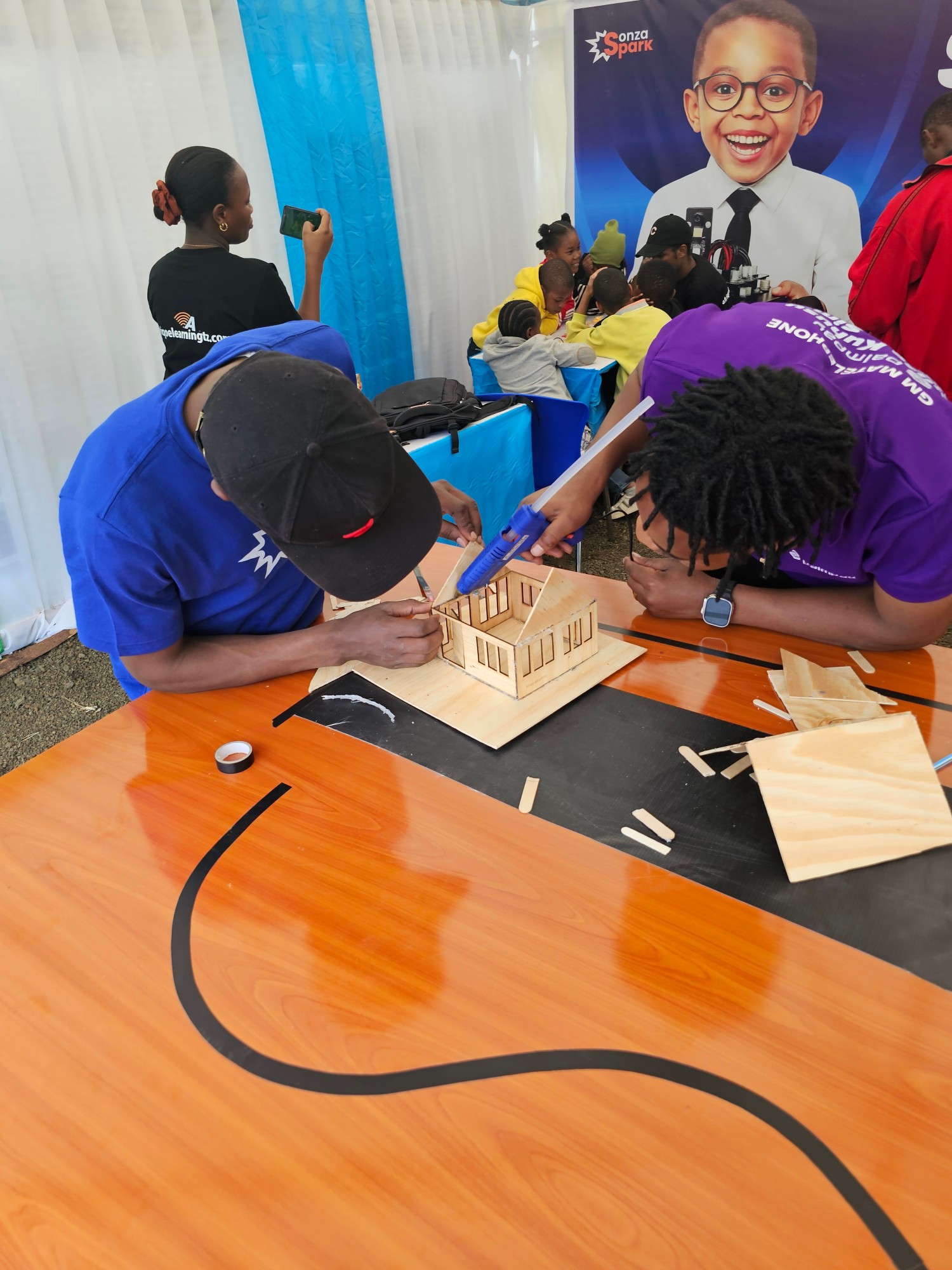 SonzaSpark team at a Tanzanian exhibition building a wooden model house